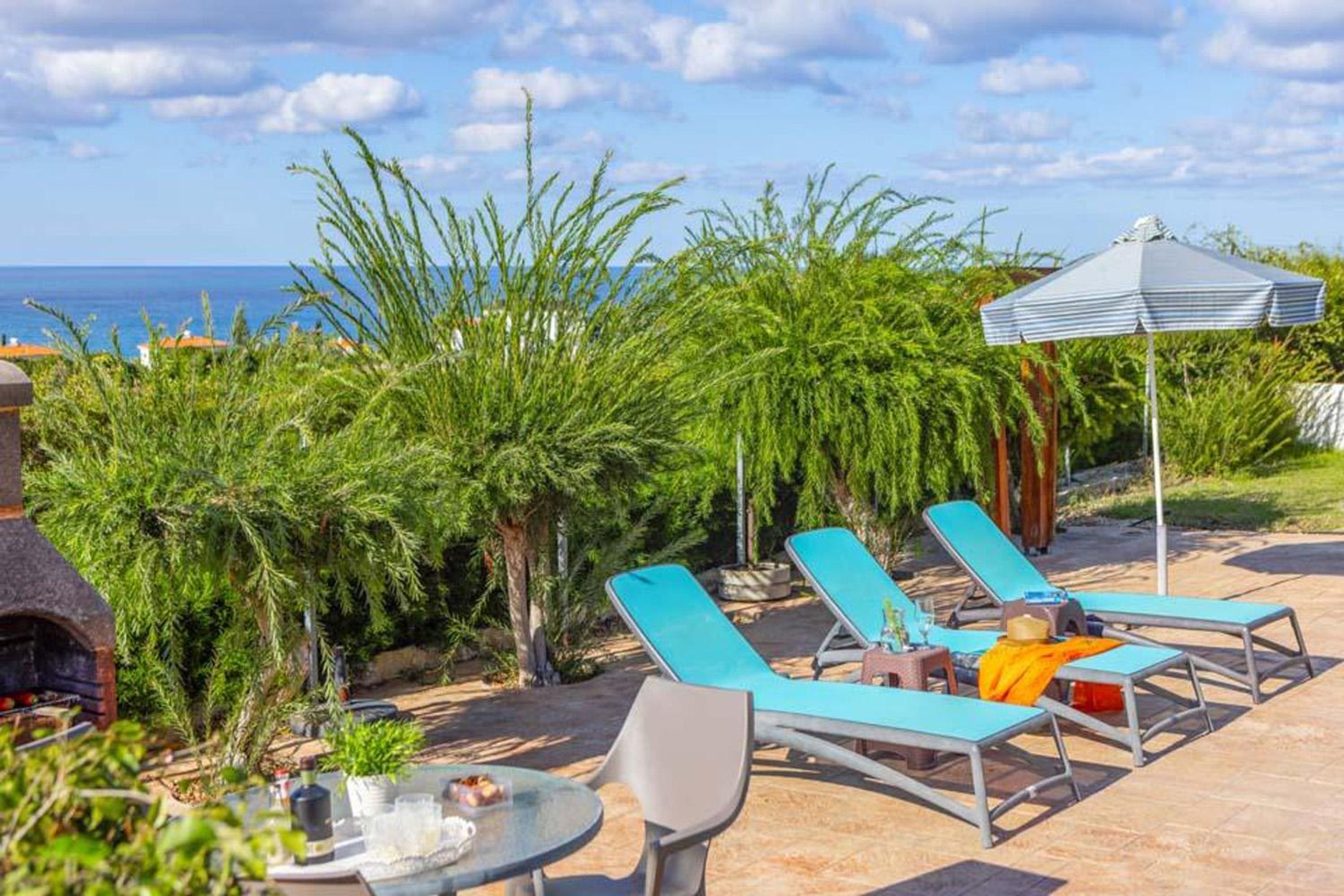 A patio with lounge chairs, a table, and a grill.