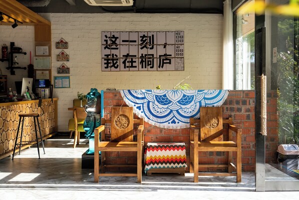 A room with a brick wall, a wooden bench, a patterned tablecloth, and a sign with Chinese characters.