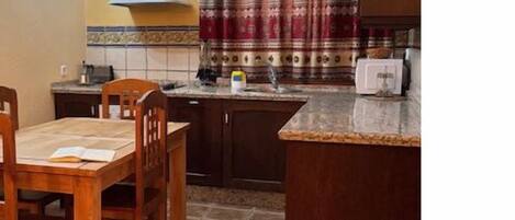 A kitchen with a dining table, chairs, a stove, and a microwave.
