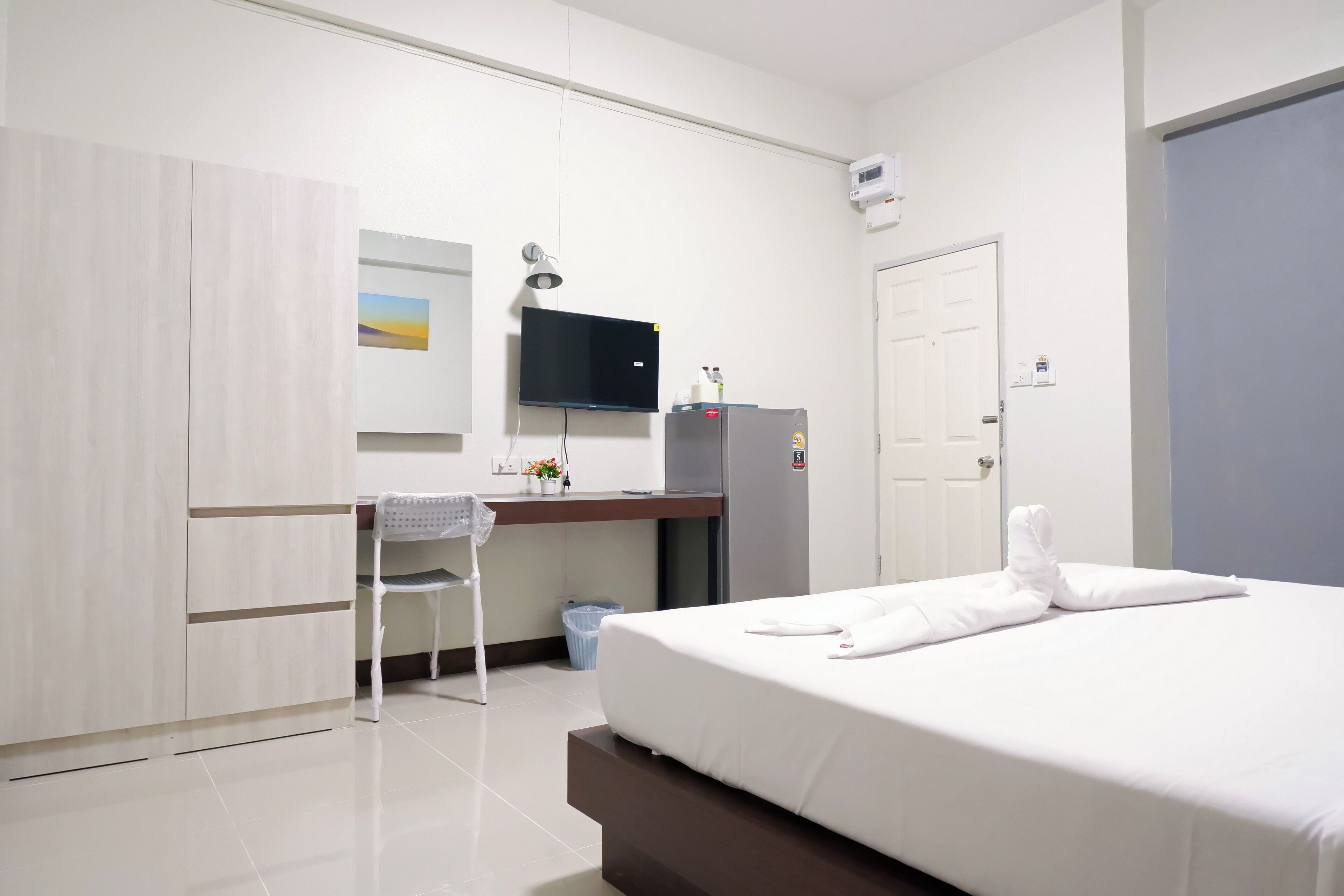 A hotel room with a bed, a desk, a chair, a TV, and a wardrobe.