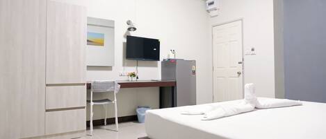 A hotel room with a bed, a desk, a chair, a TV, and a wardrobe.
