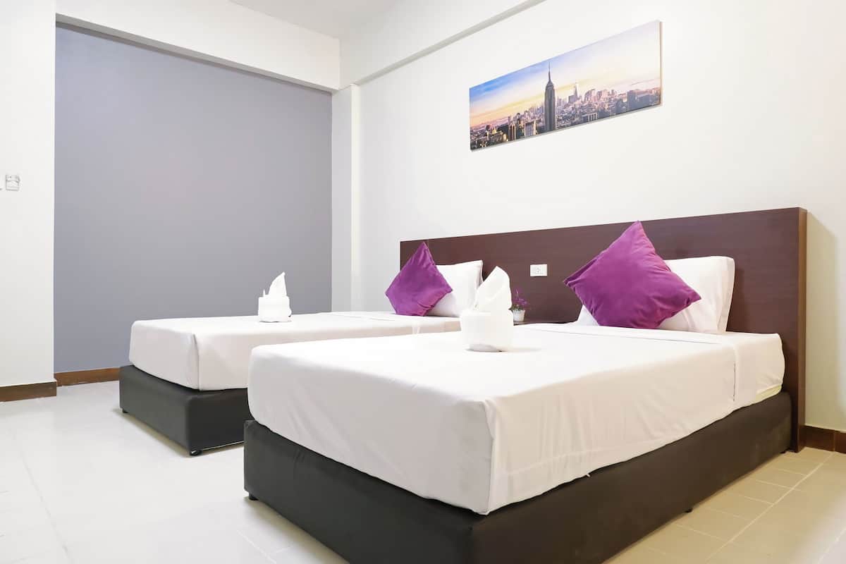 Habitación de hotel con dos camas, cada una con ropa de cama blanca y almohadas moradas, un cuadro de paisaje urbano en la pared y un diseño moderno.