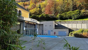 A building labeled 'PISGINE' with a pool, surrounded by greenery and a stone wall. - Apartment 2/4/6 pers. HYPER CENTRE, quiet (dead end) with PARKING, linen provided (Cauterets)