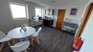 Una cocina compacta con comedor, un refrigerador pequeño, un microondas y una cafetera.