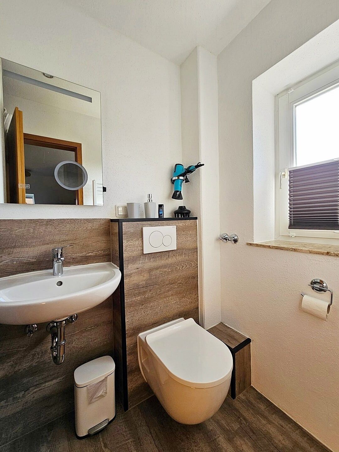 Une salle de bain moderne avec un lavabo, un miroir et des toilettes, le tout de couleur blanche.