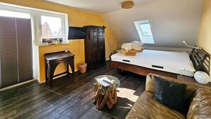 Un dormitorio con cama, un armario de madera, una mesita, un sofá y una ventana con persianas.