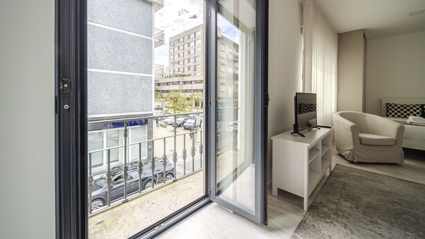 Un appartement moderne doté d’un balcon, d’un canapé, d’un meuble pour la télévision et offrant une vue sur le paysage urbain.