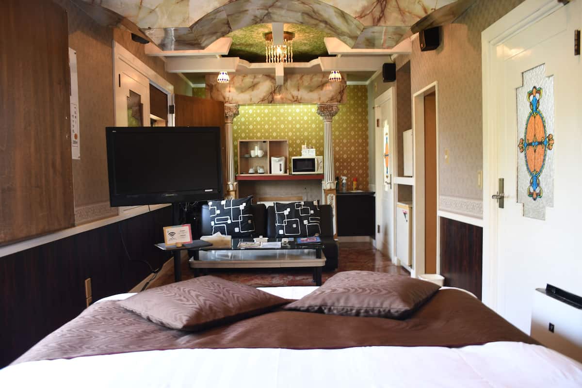 Una camera d'albergo con un letto, una televisione, un tavolino da caffè e un angolo cottura.