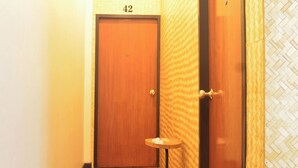 A hallway with wooden flooring, a door labeled "42", and a small table. - Sweety Secret Guesthouse (Bangkok)