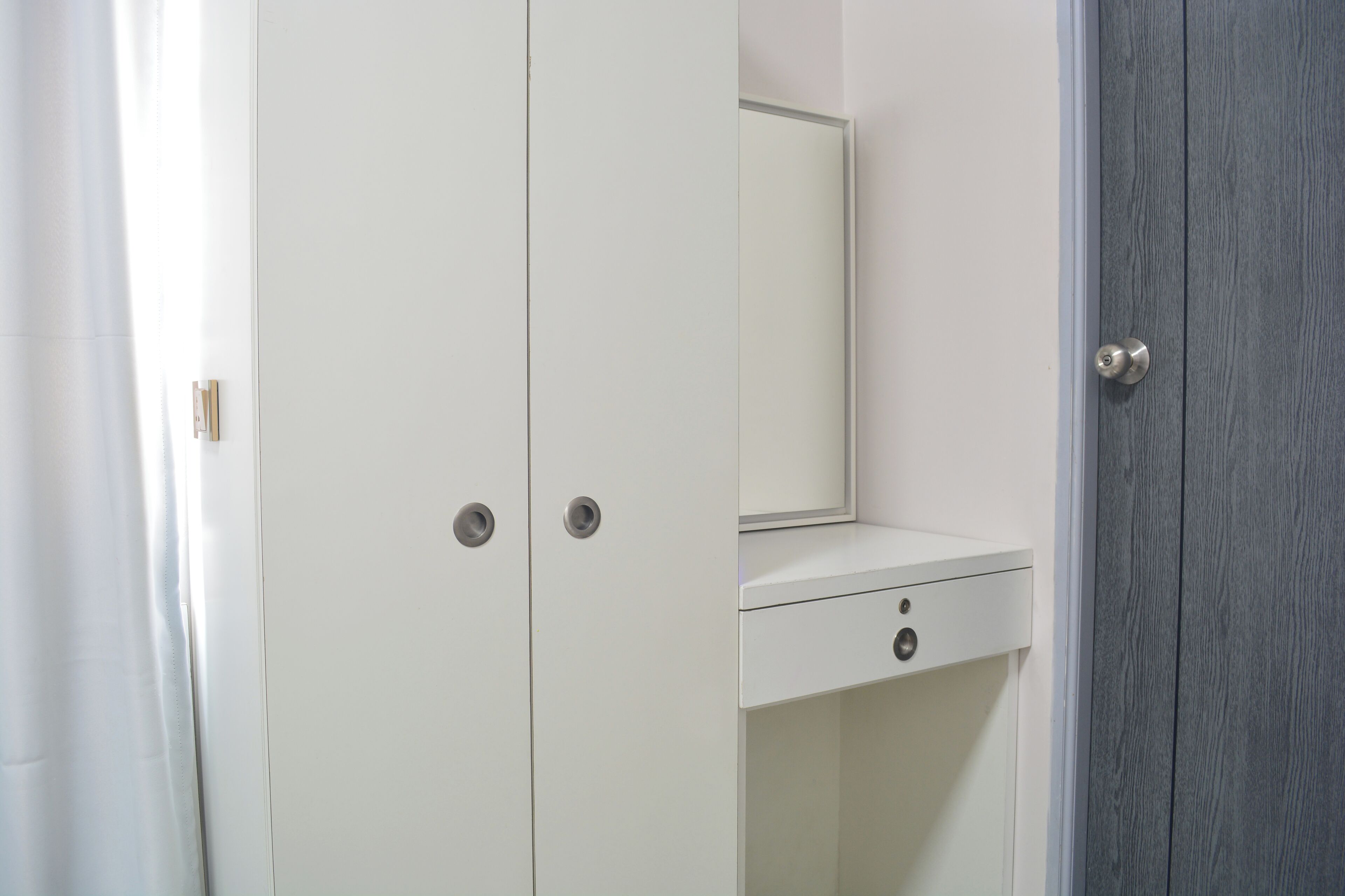 A white wardrobe with a mirror and a small drawer.