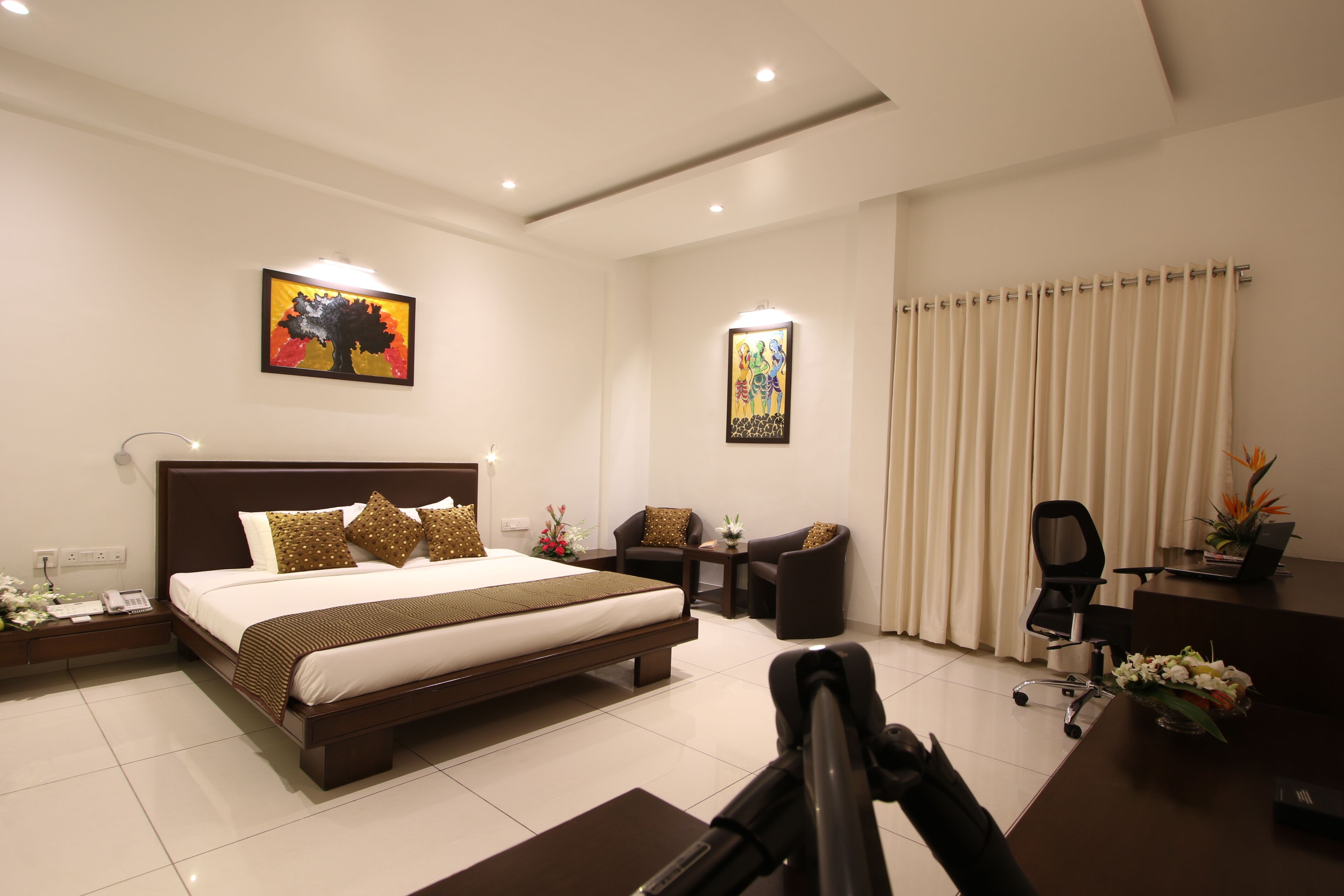 A hotel room with a large bed, two chairs, a desk, and a computer.