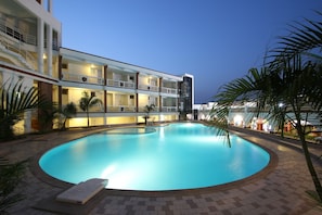 A modern hotel with a swimming pool, multiple balconies, and a well-lit exterior. - Prakruti Resort (Vadodara)