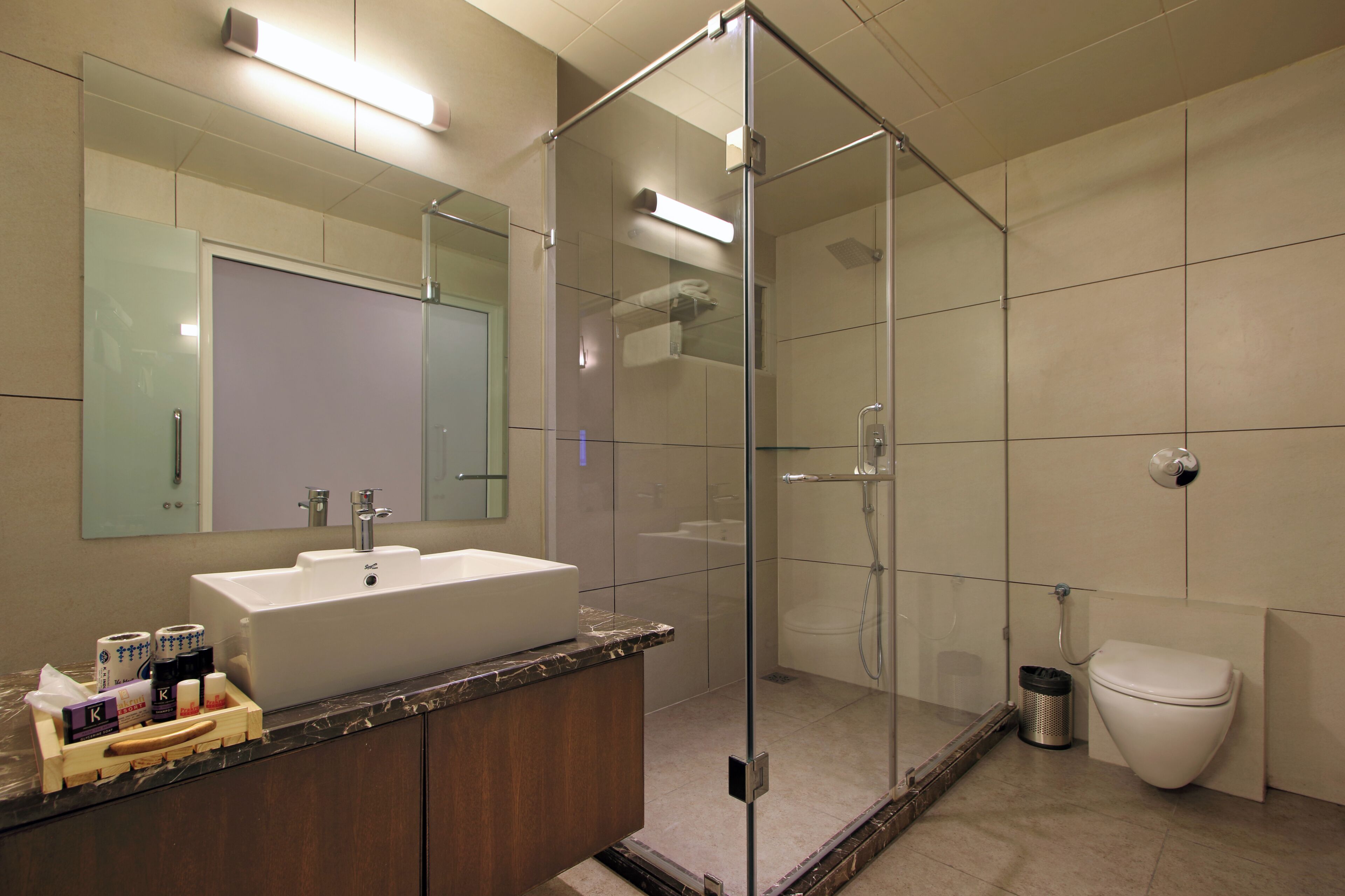 Un baño moderno con ducha envuelta en cristal, un lavabo blanco y un inodoro.