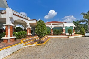 A building with a covered entrance, a paved driveway, and a clear blue sky. - Prakruti Resort (Vadodara)