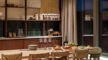 A dining area with a wooden table set for a meal, surrounded by wicker chairs.