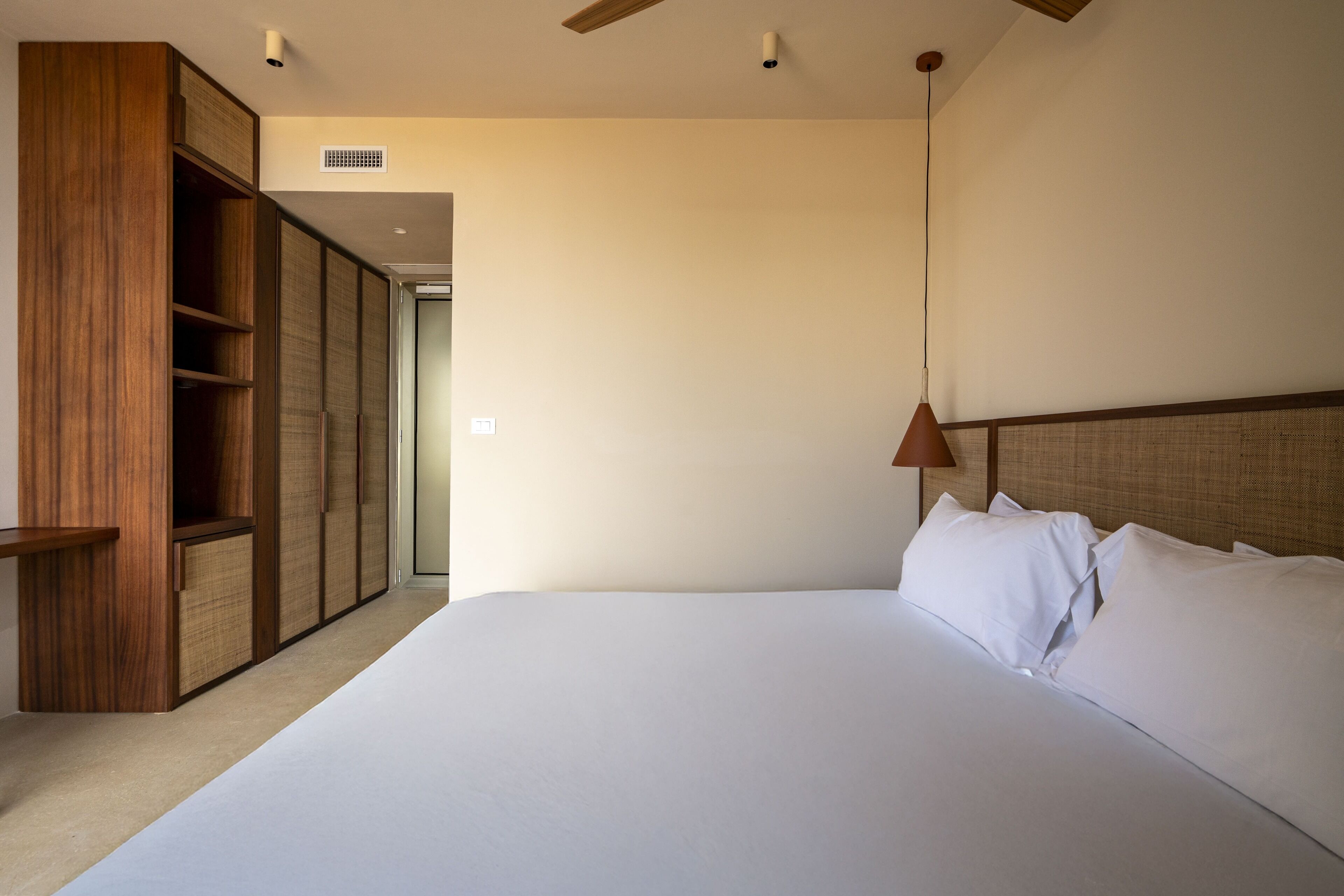 Un dormitorio con una cama grande, armario de madera y ventilador de techo.