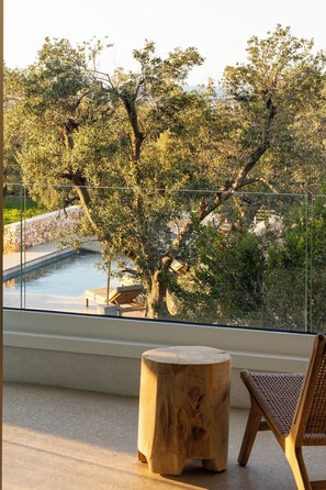 A balcony with a view of a swimming pool, surrounded by trees. - Botanico Villa & Suites (Carovigno)