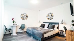 A modern bedroom with a bed, two chairs, a small table, and artwork on the walls. - Hotel am Schafbaum (Bad Rappenau)
