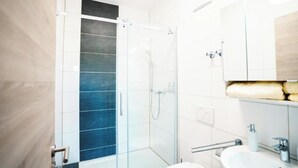 A modern bathroom with a glass shower enclosure, a white sink, and a wooden vanity. - Hotel am Schafbaum (Bad Rappenau)