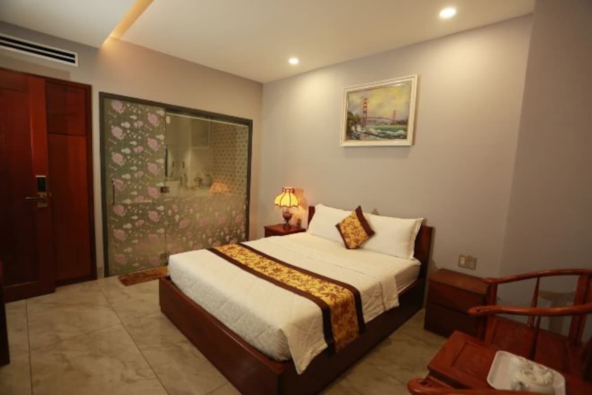 A bedroom with a bed, a nightstand, a chair, a painting, and a door with a floral design.