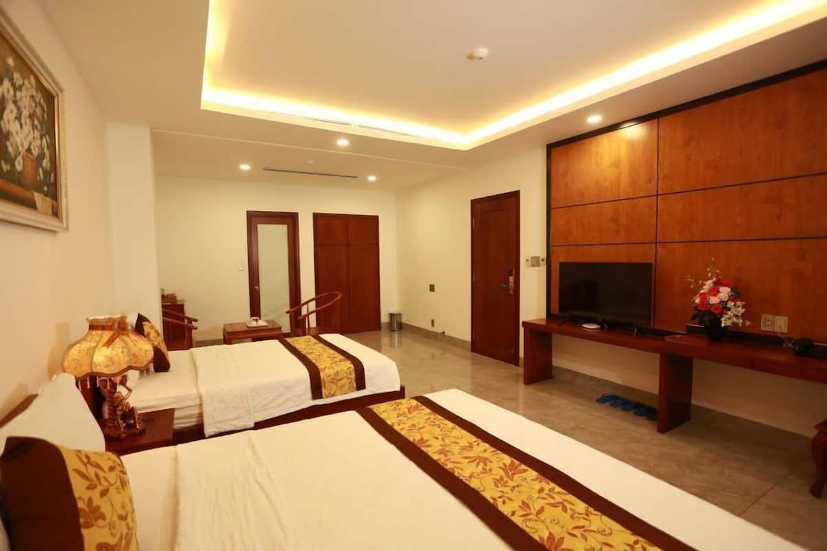 Habitación de hotel con dos camas, un televisor, un escritorio y un armario de madera grande.