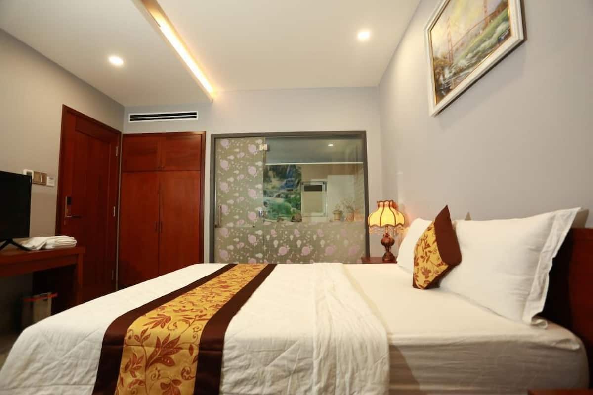 Una habitación de hotel con cama, escritorio, silla, lámpara y un cuadro en la pared.