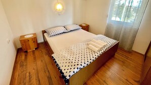 Un dormitorio con una cama grande, cabecera de madera, dos mesitas de noche y una ventana con cortinas.
