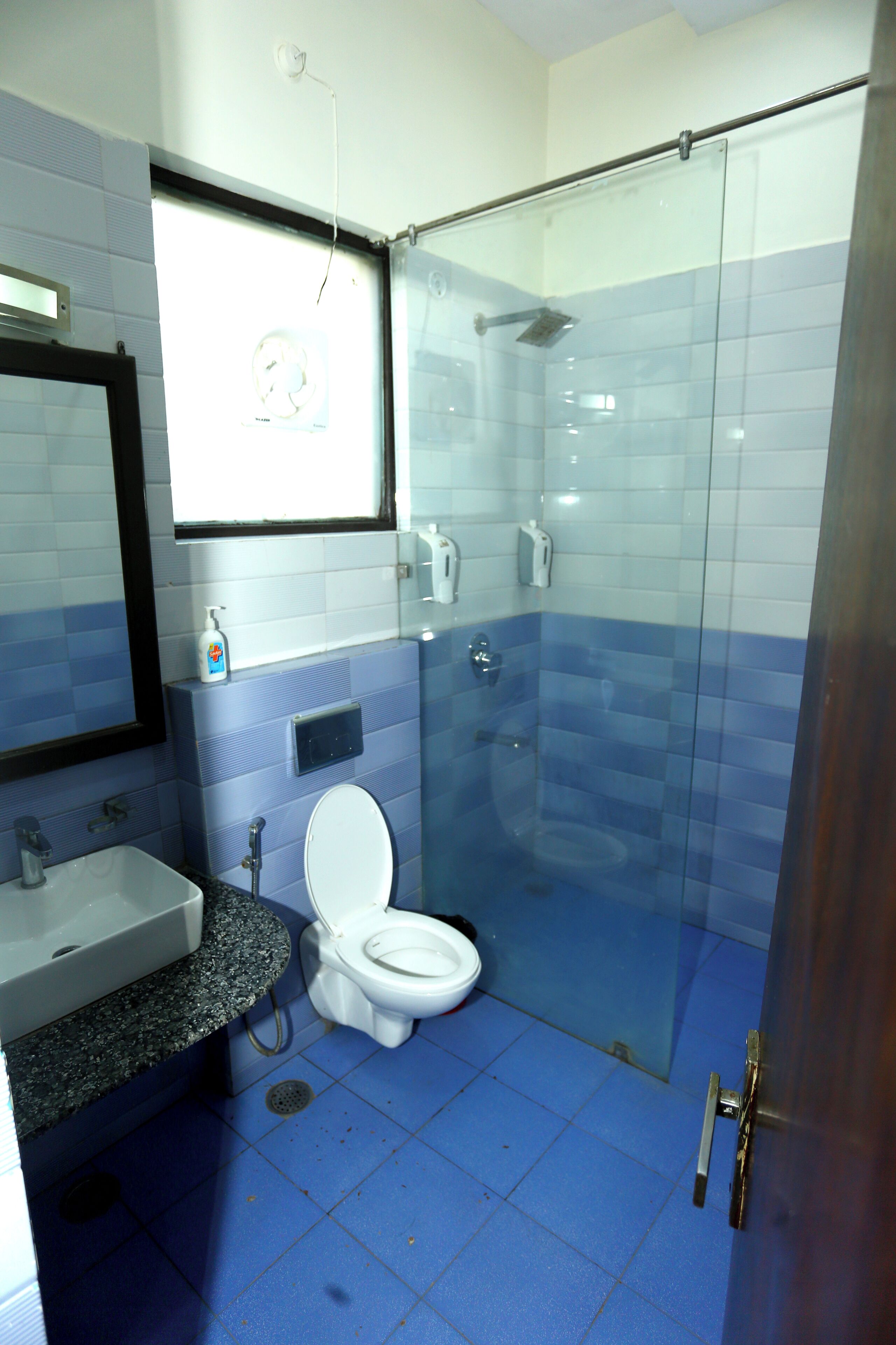 Un baño con lavamanos, inodoro y cabina de ducha con mampara de vidrio.