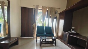 A spacious living area with a sofa, a coffee table, and a television. - De Floresta resort (Ramnagar)