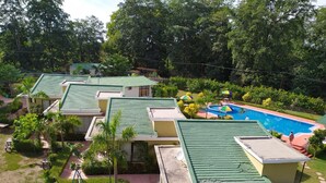 A resort with multiple buildings, a swimming pool, and lush greenery. - De Floresta resort (Ramnagar)