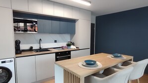 A modern kitchen with white cabinets, a wooden island, and a blue accent wall.