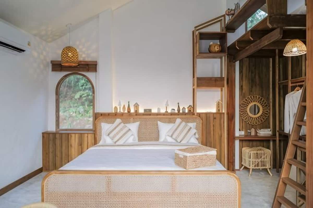 A bed with a wooden headboard, a wicker footboard, and a bedside table with a lamp.