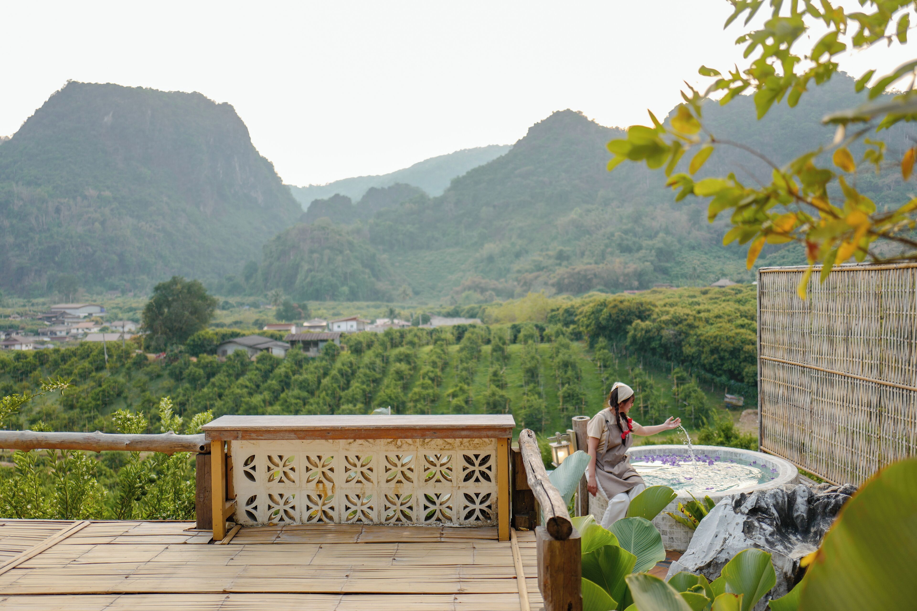 A person standing by a hot tub with a mountainous backdrop.