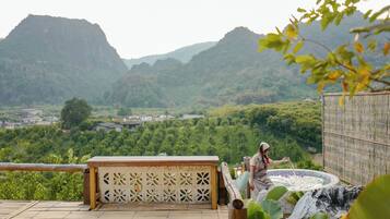 A person standing by a hot tub with a mountainous backdrop.