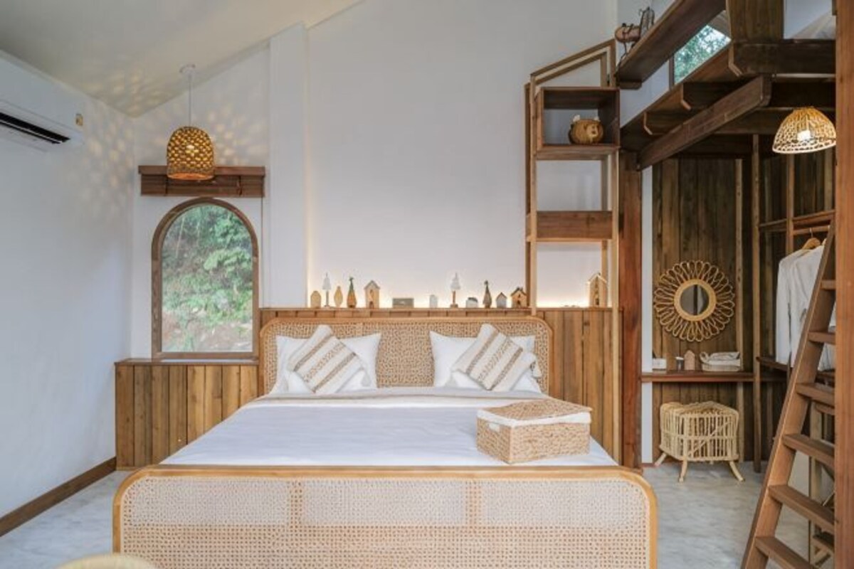 A bed with a wooden headboard, a wicker footboard, and a bedside table with a lamp.