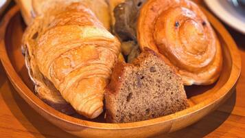 Una bandeja de madera con croissants y pan sobre una mesa.
