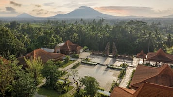 A traditional Balinese village with terraced fields, a temple, and a mountain in the background.