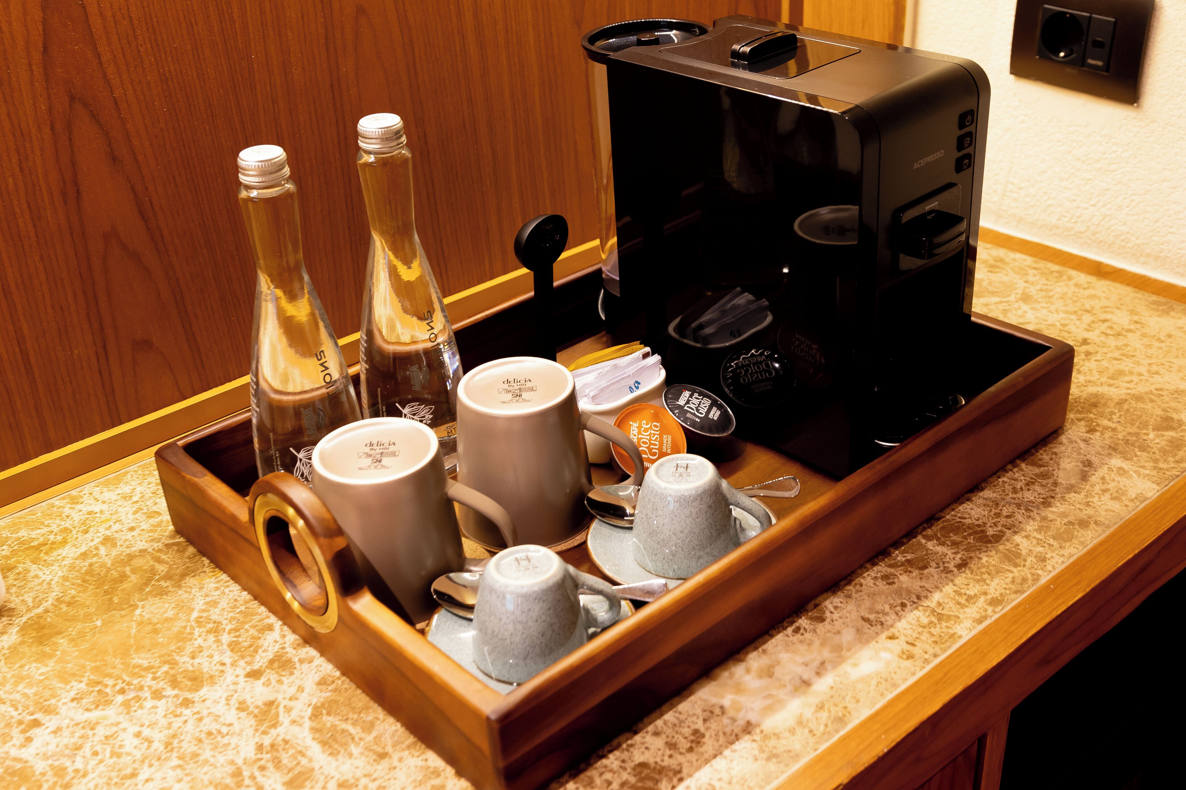 A tray with coffee-making equipment and various cups and bottles on a countertop.