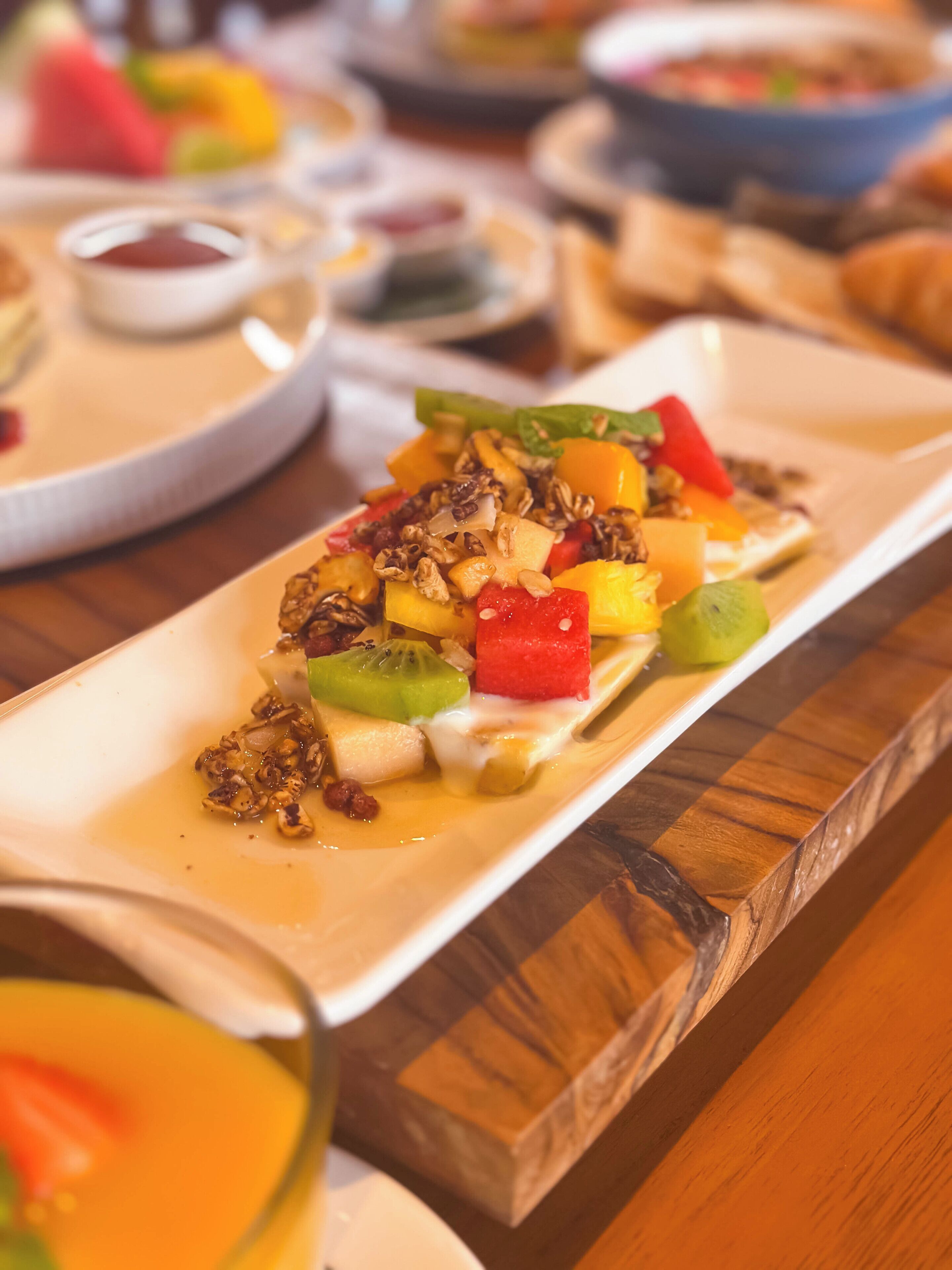 Un plato de postre con fruta y frutos secos sobre una mesa de madera.