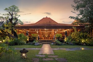 A traditional building with a tiled roof, a central entrance, and a well-maintained garden with stone pathways and plants.
