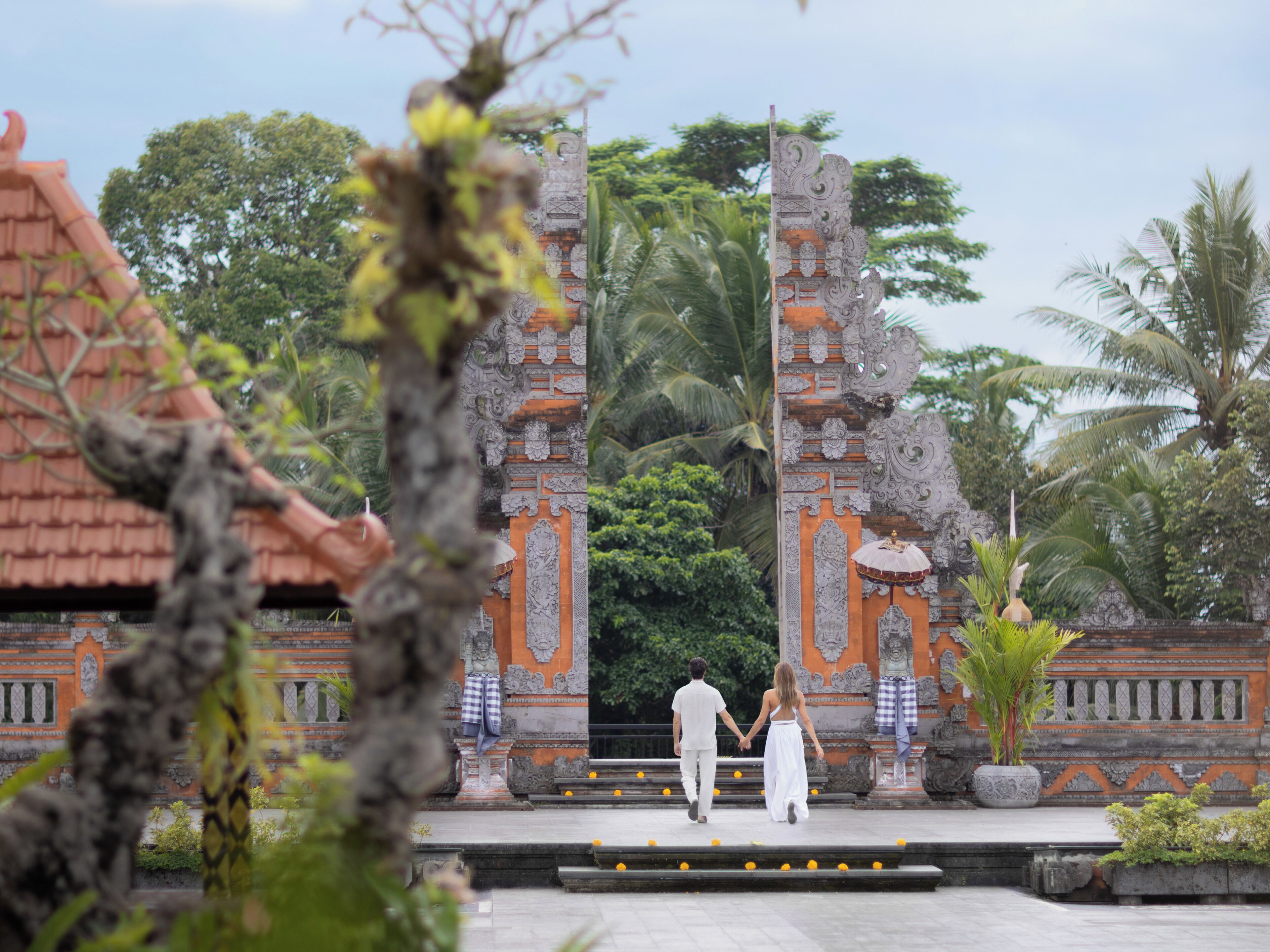 A couple walking through a temple entrance with intricate carvings and a traditional roof.