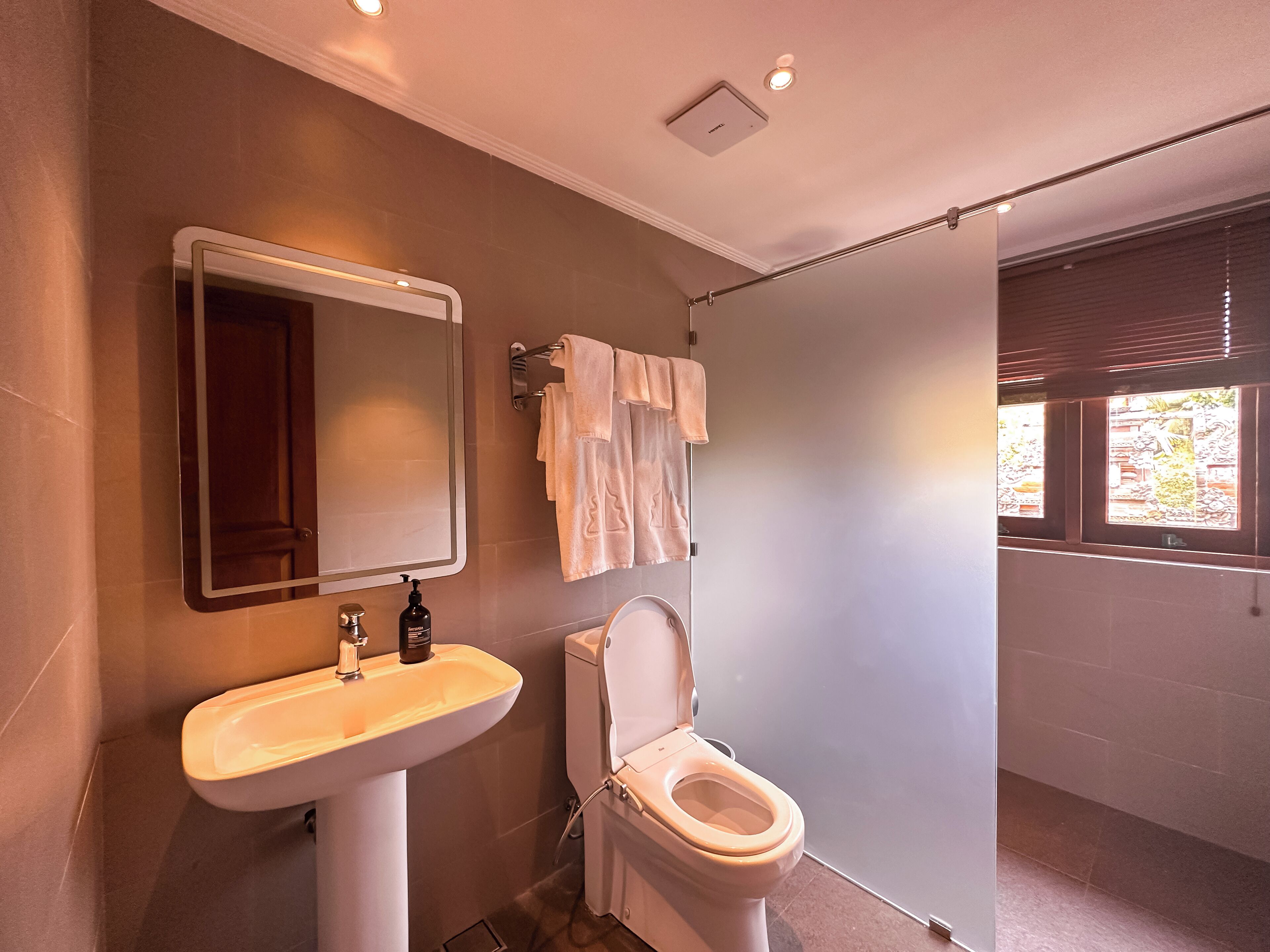 Un baño moderno con lavamanos, espejo, inodoro y toallero.