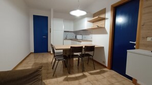 A compact kitchen with white cabinets, a wooden dining table, and two chairs. - Seaside Escape for six Guests in Bibione (San Michele al Tagliamento)