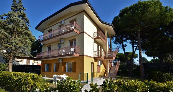 A multi-story building with balconies, air conditioning units, and a staircase leading to an upper level.