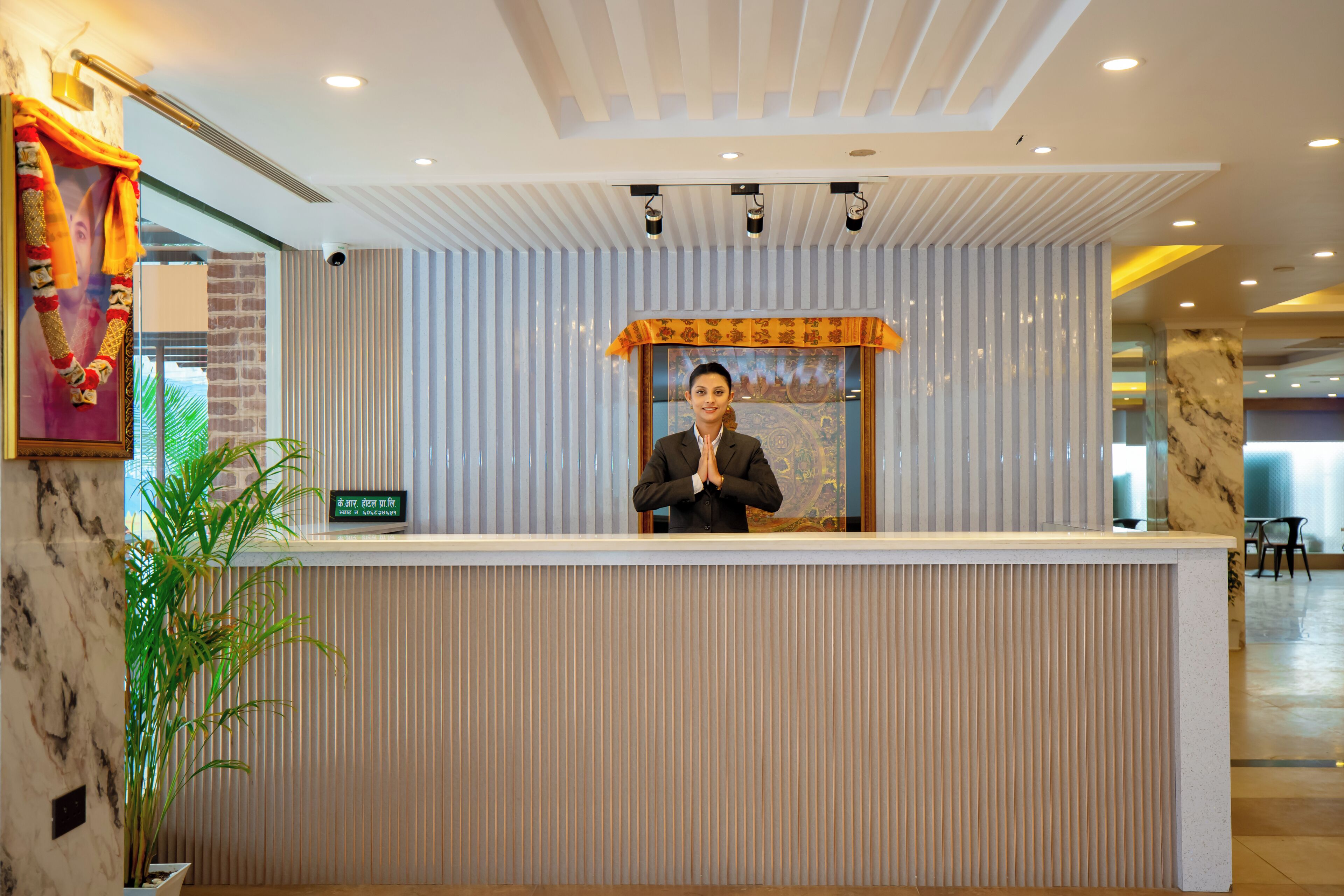 A reception desk with a modern design, a potted plant, and a framed picture on the wall.
