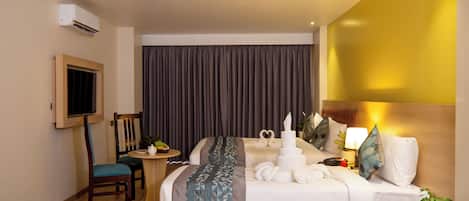 A hotel room with a bed, bedside table, lamp, and a TV mounted on the wall.
