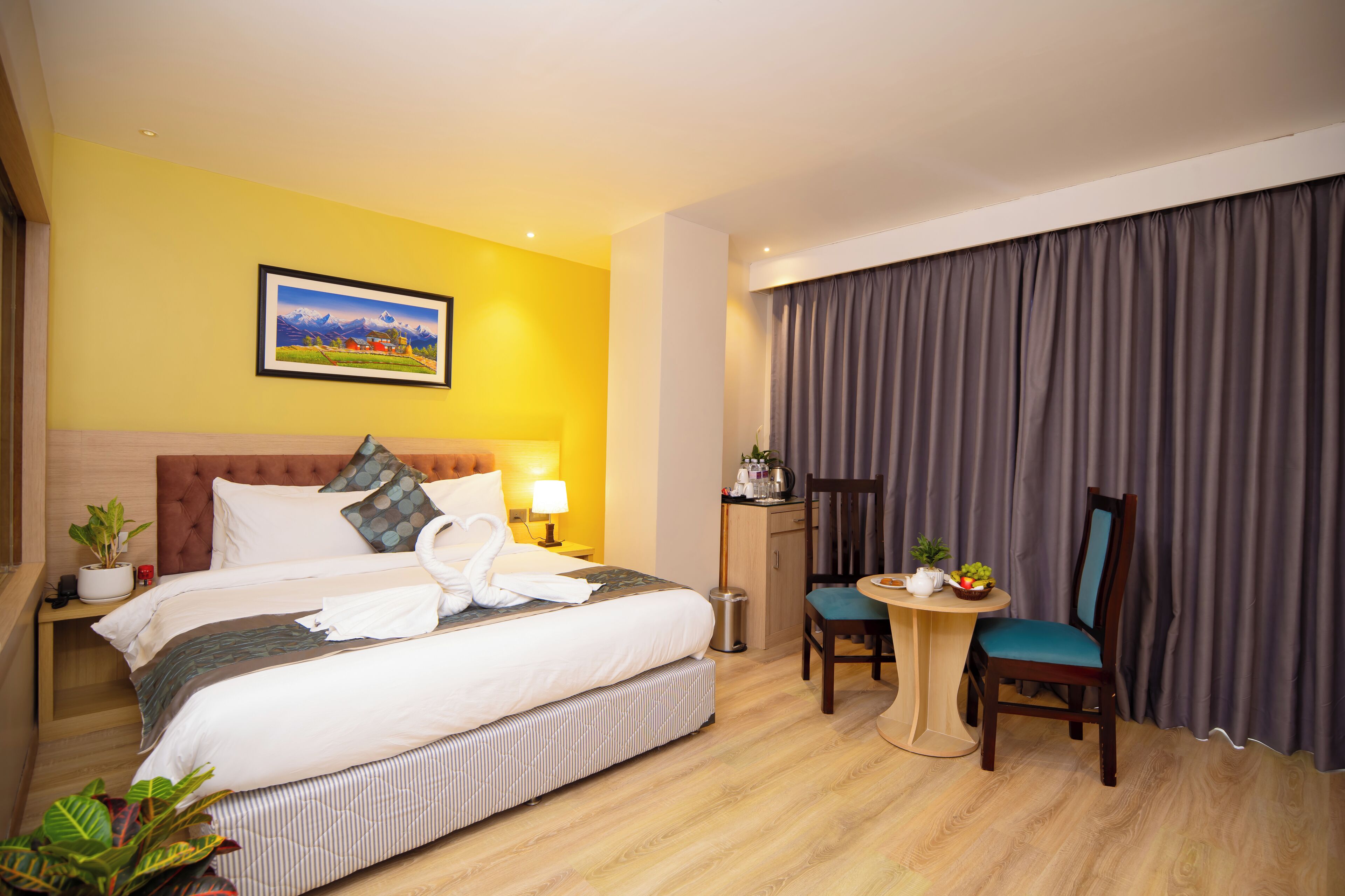 Una habitación de hotel con cama, mesita de noche, lámpara, silla y escritorio con otra silla.