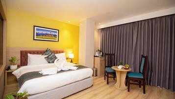 Una habitación de hotel con cama, mesita de noche, lámpara, silla y escritorio con otra silla.