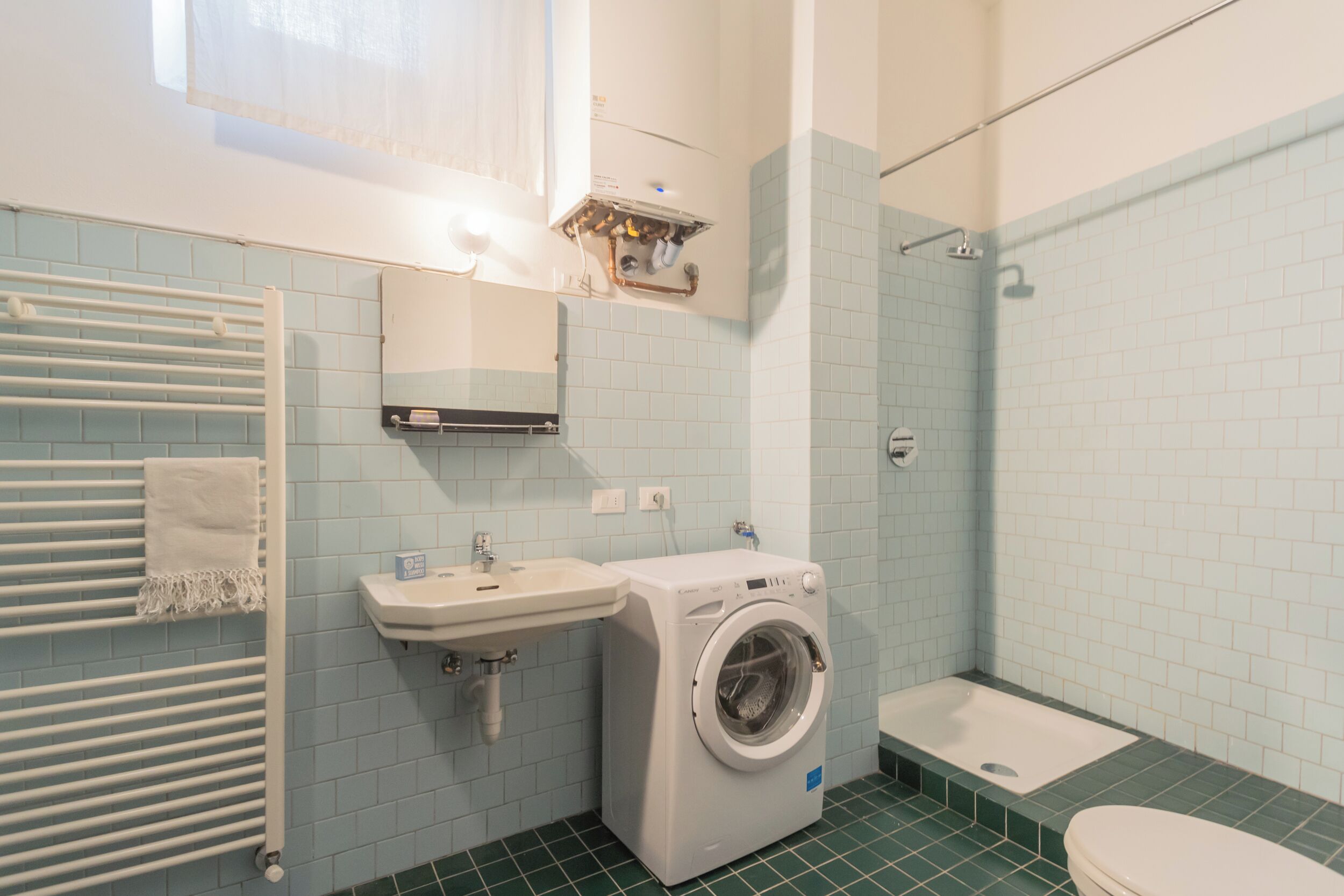 A bathroom with a washing machine, sink, and toilet.