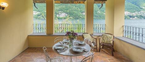 Un coin repas avec une table dressée pour quatre personnes, offrant une vue imprenable sur un lac et des montagnes.
